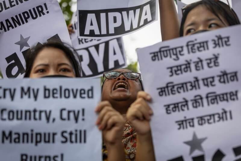 印度東北省分5月間發生種族暴亂，近日傳出暴民將兩名女子脫光遊街事件，引發印度民眾怒火，抗議者21日手舉標語在街上吶喊。（路透社）