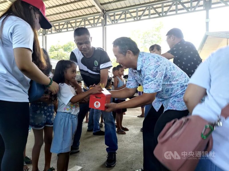 中華民國駐菲律賓代表周民淦（右藍衣者）9日參與台商赴原住民社區捐助物資活動，將物資交給原住民小朋友。中央社記者陳妍君蘇比克灣攝  112年7月23日