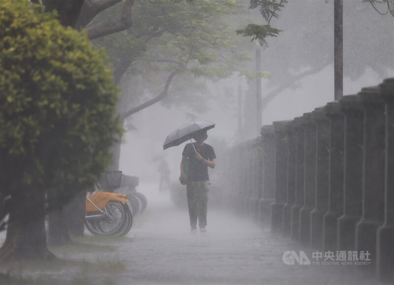 圖為12日台北市中正區民眾撐傘走在大雨中。（中央社檔案照片）