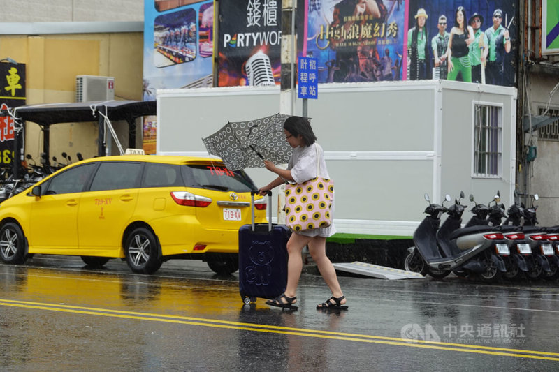 颱風杜蘇芮來襲，26日中午過後恆春地區風雨增強，街頭民眾連傘都撐不住，一手推著行李箱，一手只能緊抓已經「開花」的傘骨。中央社記者李卉婷攝  112年7月26日