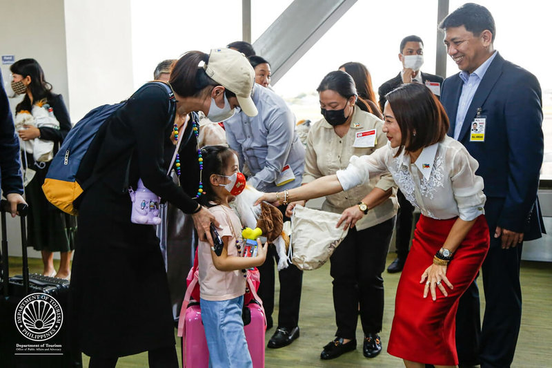 8月24日起，中國公民將可申請電子簽證前往菲國。圖為菲律賓觀光部長佛拉斯科（Christina Frasco，紅裙者）1月24日在機場迎接抵菲的中國旅客。（菲律賓觀光部提供）中央社記者陳妍君馬尼拉傳真  112年7月26日