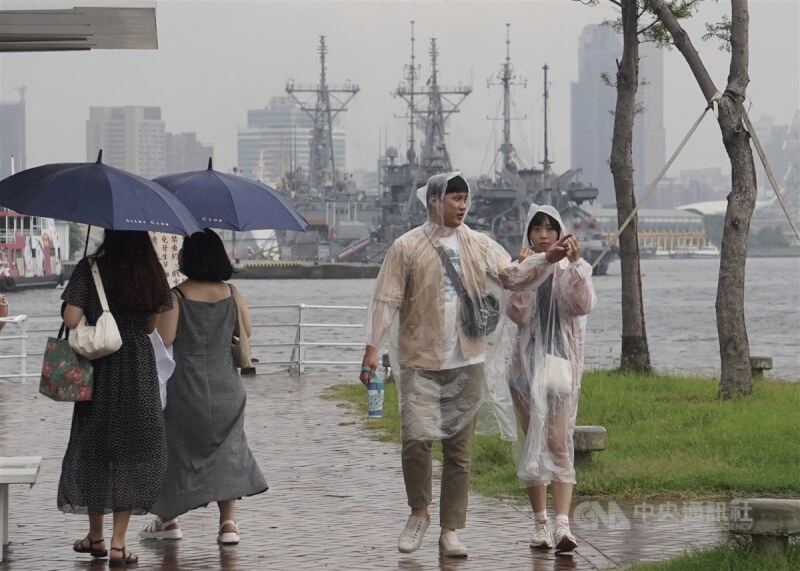 颱風杜蘇芮來襲，風雨造成台南市、高雄市及台東縣等局部地區停電。圖為26日高雄市鼓山區午後下起陣雨，民眾穿雨衣、撐傘躲避雨勢。（中央社檔案照片）