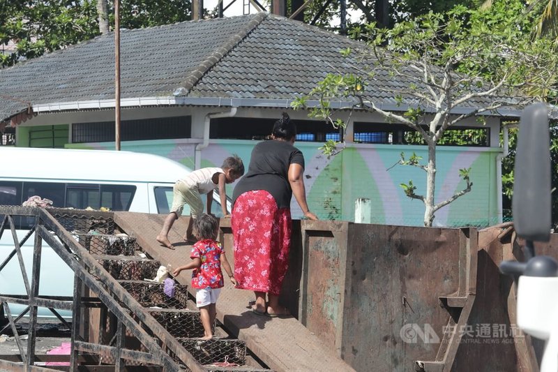東馬沙巴拿篤漁市場外，一名帶著兩名幼童的母親在階梯上望著大型垃圾箱內有否食物。中央社記者黃自強沙巴攝 112年7月29日