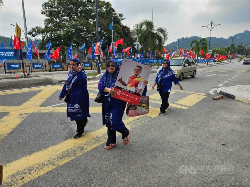 馬來西亞即將舉行6州選舉，朝野陣營於29日提名日後展開競選，圖為支持團結政府選民手持候選人牌子行經雪蘭莪州鵝嘜雙溪布蘇國民中學提名中心。圖攝於29日。中央社記者黃自強吉隆坡攝 112年7月31日