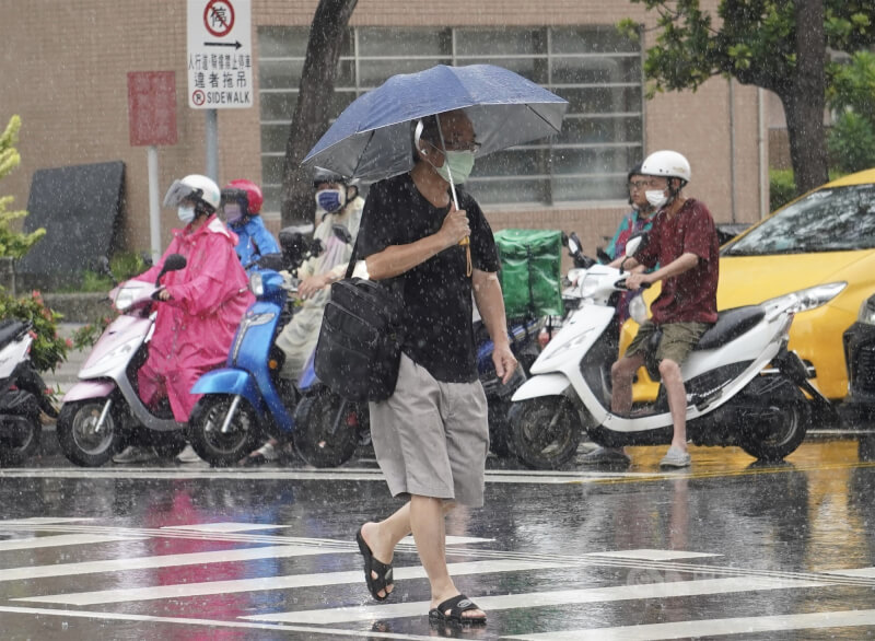 圖為高雄市三民區午後下起雨，機車騎士穿起雨衣遮擋雨勢，行人也撐傘走避。（中央社檔案照片）