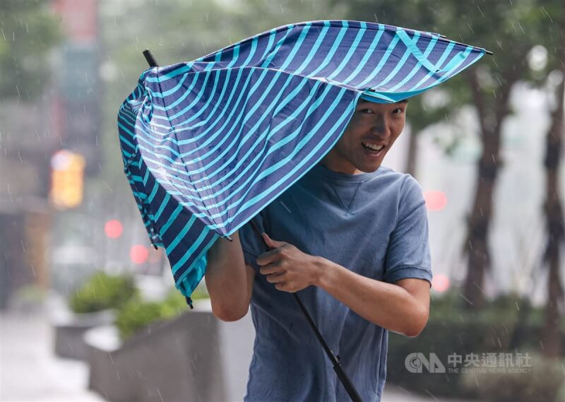 颱風卡努龜速前進，預估最接近台灣時間點落在3日深夜至4日凌晨，靠近台灣過程中，北部、東北部各地風雨將逐漸增強。圖為台北市中正區民眾3日撐傘外出，雨傘被強風吹到變形。中央社記者鄭清元攝 112年8月3日