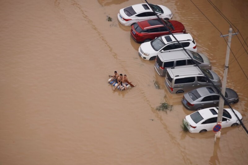 2021年7月中國河南水患，街道被黃泥水淹沒，民眾只能搭著小筏移動。（路透社）