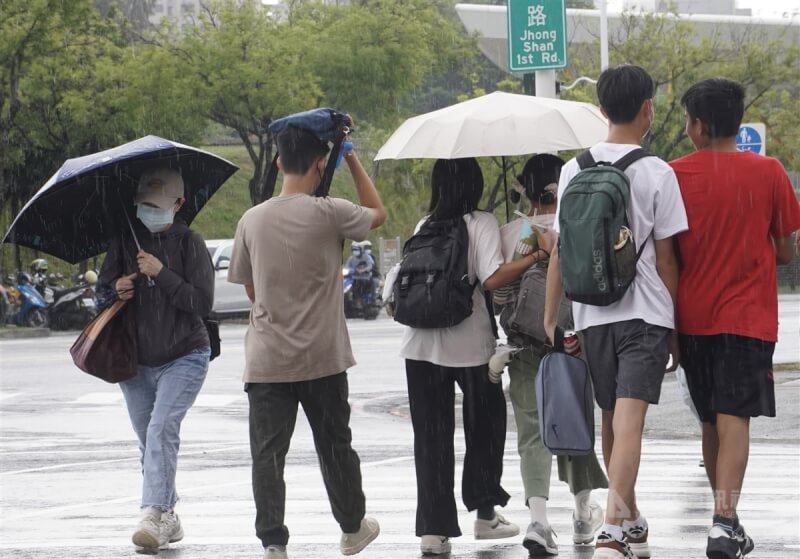 圖為高雄市新興區下起陣雨，路上有民眾撐傘避雨、也有人無畏細雨繼續行走。（中央社檔案照片）