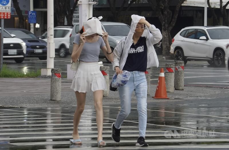 中南部7日有不定時短暫陣雨或雷雨，南部地區及中部山區仍易有局部大雨，台北盆地及花東縱谷內須防38度高溫。圖為高雄市區午後下起陣雨，行人以隨身物品勉強遮擋雨勢。（中央社檔案照片）