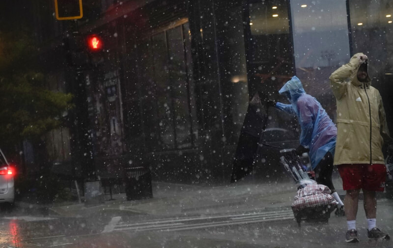 7日華盛頓特區暴風雨，民眾過馬路時，雨傘被風吹得外翻。（法新社）