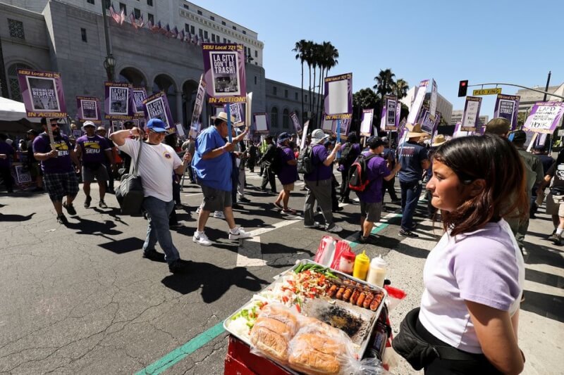 好萊塢編劇和演員兩大工會成員聯手罷工，整個洛杉磯商業活動幾乎停擺。圖為罷工遊行現場擺攤的攤販。（路透社）