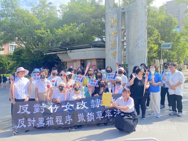 「反對國立新竹女中改隸陽明交通大學附屬中學」連署行動11日上午在新竹女中校門口舉行，多名校友、退休職員等持鮮花、標語表達訴求。中央社記者魯鋼駿攝 112年8月11日