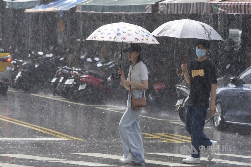 圖為台北市迪化街，民眾遇大雨撐傘過馬路。（中央社檔案照片）