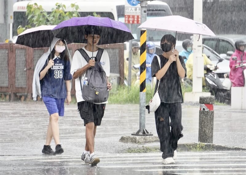 圖為高雄市新興區午後下起一陣大雨，民眾撐傘遮擋雨勢。（中央社檔案照片）