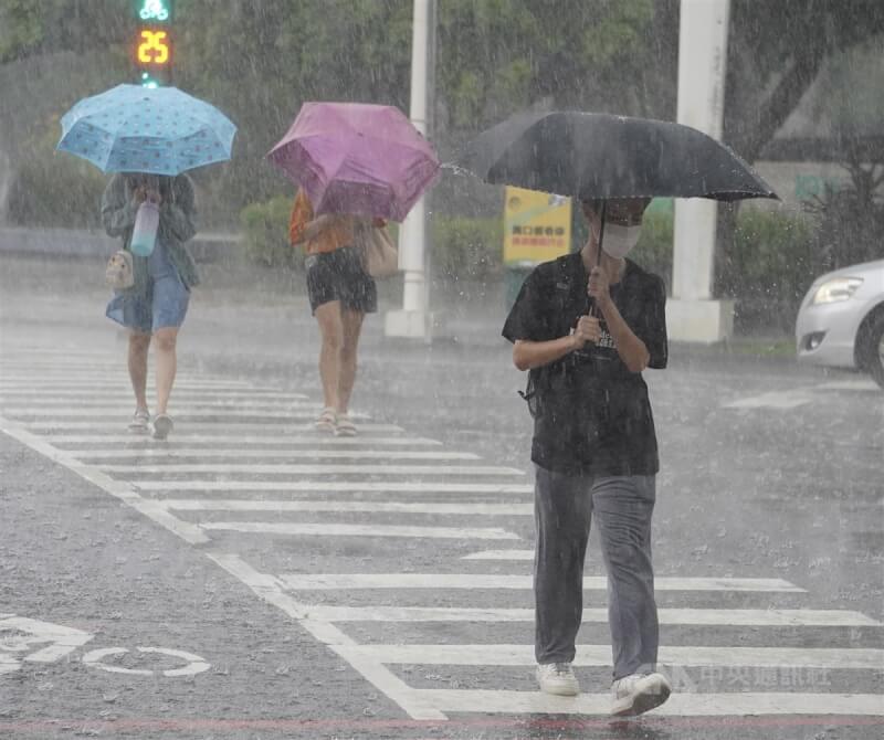 高雄市新興區下起大雨，行人紛紛撐傘走避。（中央社檔案照片）