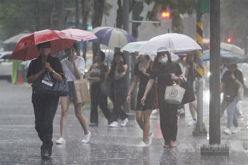 氣象局17日下午針對台北、新北發布大雷雨即時訊息。圖為台北市信義區民眾撐傘快步過馬路。（中央社檔案照片）