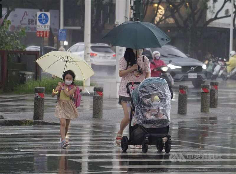 氣象局表示，17日各地天氣不穩定且降雨機率高，西半部地區整天有陣雨或雷雨，尤其中南部地區清晨後雨勢更明顯。圖為高雄市新興區午後下起陣雨，民眾撐傘帶孩子快步過馬路。（中央社檔案照片）