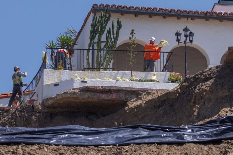 颶風希拉里將登陸南加州，圖為加州聖克里門提，工人們用防水布覆蓋滑坡嚴重的山坡。（路透社）