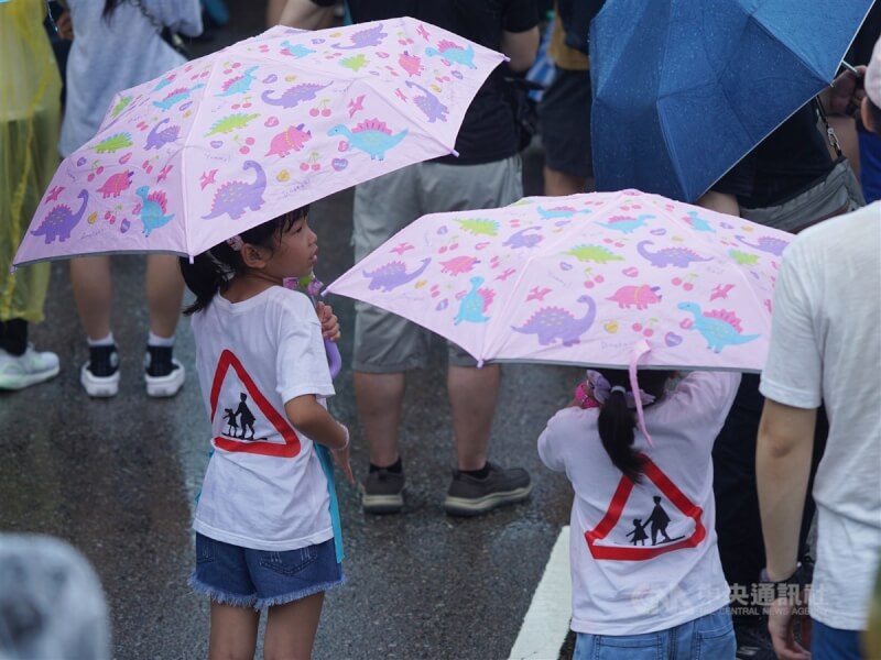 由民團發起的「還路於民大遊行」20日遇到午後大雨，穿著印有「當心兒童」標誌T恤的小朋友撐傘參與。中央社記者徐肇昌攝 112年8月20日