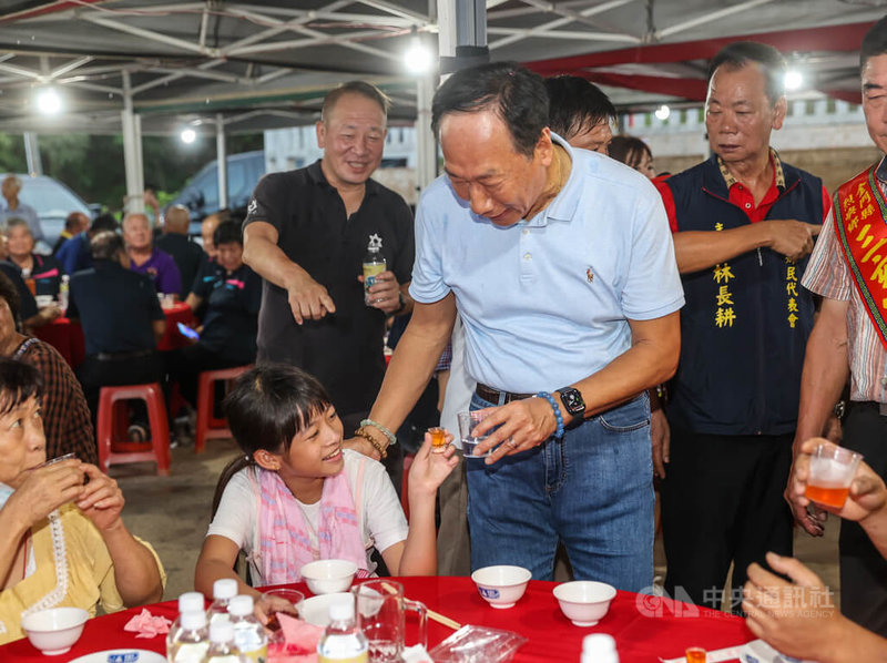 鴻海創辦人郭台銘（前右）22日晚間參加烈嶼三玄宮醮慶活動，席間與民眾舉杯致意，有小朋友拿起飲料與郭台銘敬酒。中央社記者鄭清元攝 112年8月22日