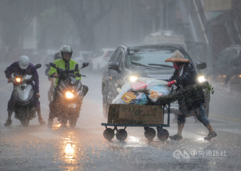 中央氣象局22日發布大雨特報，午後對流雲系發展旺盛，易有短延時強降雨。圖為台北市中正區民眾戴著斗笠在雨中前行。中央社記者王飛華攝 112年8月22日