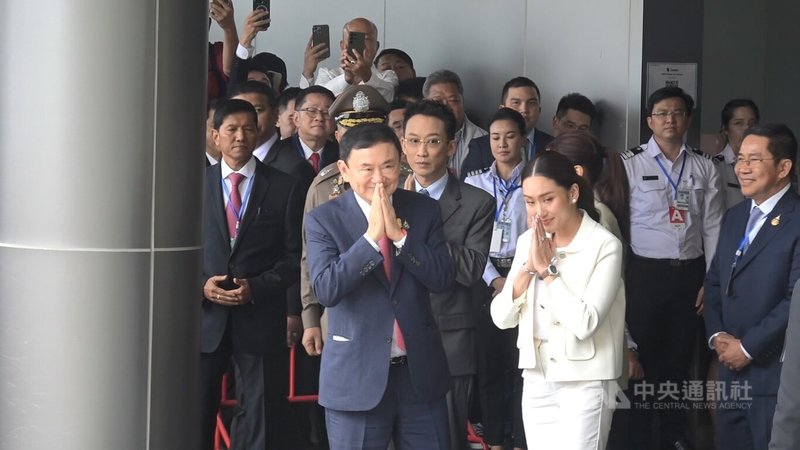 泰國流亡前總理戴克辛（中著藍色西裝者）22日早上返泰，他的私人飛機從新加坡起飛抵達曼谷廊曼機場。戴克辛在女兒貝東塔（著白色套裝者）陪同下步出機場，向媒體致意。中央社記者呂欣憓曼谷攝 112年8月22日