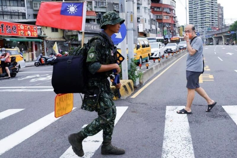 22歲的退伍士兵蔡宗霖（前）身穿迷彩服、手持塑膠步槍，在台灣徒步環島。（路透社）