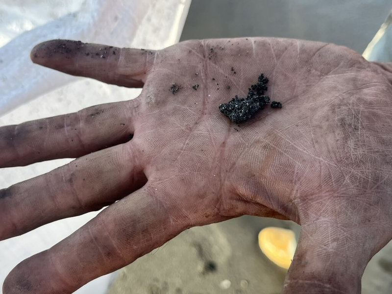 高雄旗津海水浴場出現「油球」,造成遊客身體四肢沾黏油污。高雄港務分公司27日表示,「油球」是海洋上的油污或油漬被海浪拍打上岸、來回沾沙包覆所形成;詳細污染來源仍需進一步調查釐清。(高雄港務分公司提供)中央社記者林巧璉傳真 112年8月27日