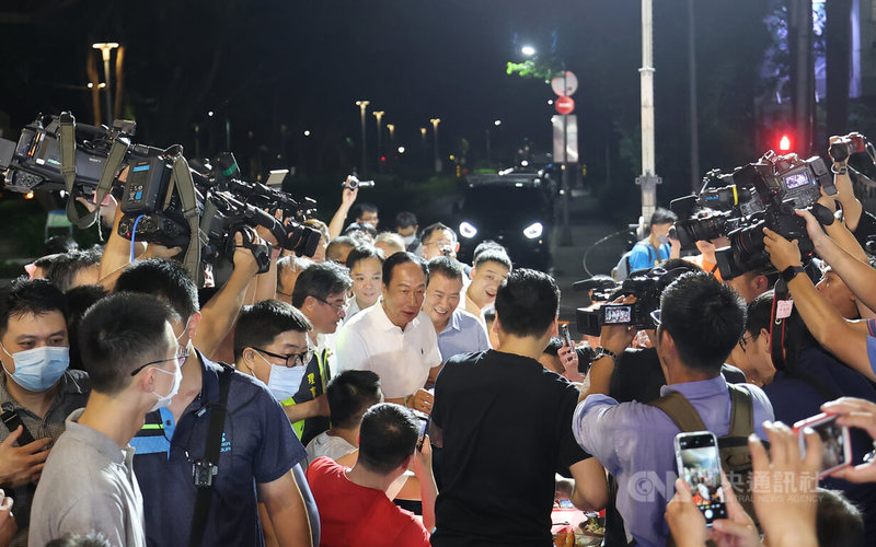 鴻海集團創辦人郭台銘(後中,白衣者)29日晚間現身台北市計程車工會普渡餐會,在媒體包圍下,逐桌敬酒以爭取支持。中央社記者趙世勳攝 112年8月29日