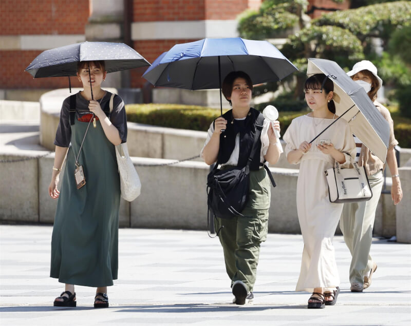 圖為東京民眾撐傘遮陽。（共同社）