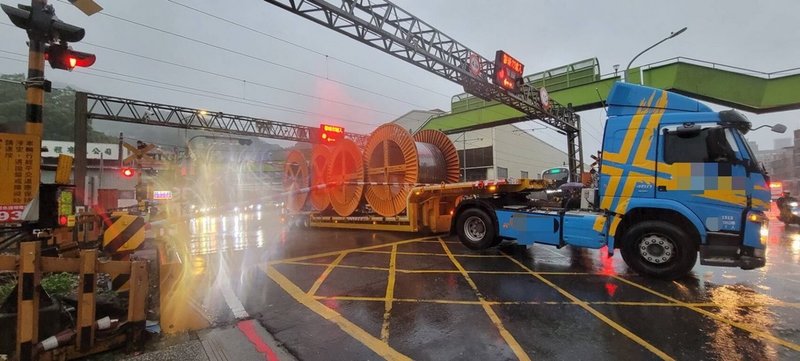 一輛載運大型電纜的拖板車6日行經新北市樹林區中山路與東佳路口平交道時,拖板車後輪卡在鐵軌間,前輪無法帶動前進,此時,平交道柵欄也剛好放下來,情況危急,幸經駕駛按下警示鈕,巡邏員警找來堆高機協助脫困,才避免可能發生的交通意外。(警方提供)中央社記者黃旭昇新北傳真 112年9月7日