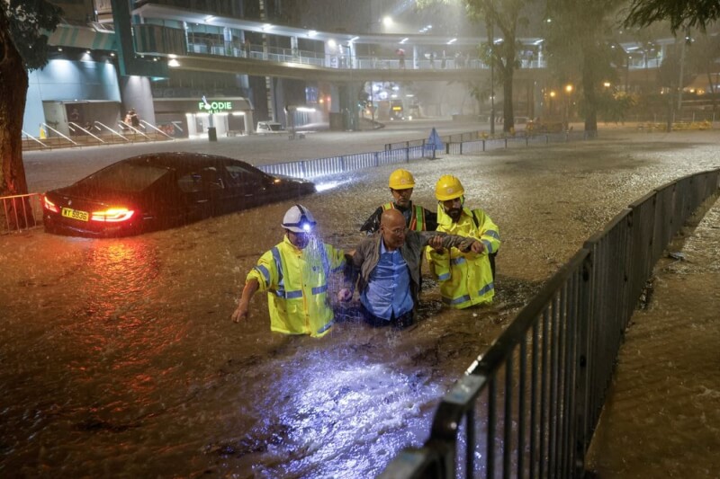 圖為香港下水道工人協助因雨受困的司機脫困。（路透社）