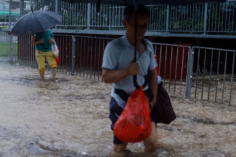香港8日道路嚴重淹水，民眾走在洪水中。（路透社）