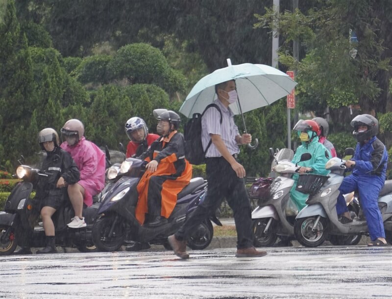 中央氣象局表示，9日持續受到低壓帶影響，各地降雨機率高。圖為高雄市新興區午後下起陣雨，機車騎士穿起雨衣遮擋雨勢，行人也撐傘走避。（中央社檔案照片）