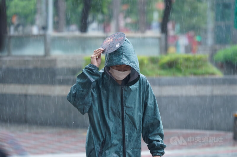 圖為中正區街頭民眾穿起連帽外套、用塑膠板勉強遮雨。（中央社檔案照片）