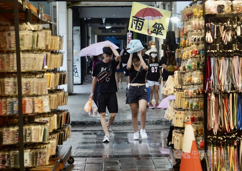 圖為高雄市新興區午後降雨，街頭有民眾以隨身物品或手掌勉強遮擋雨勢。（中央社檔案照片）