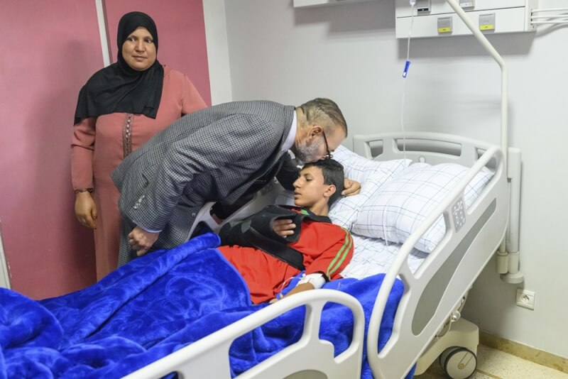摩洛哥8日強震釀近3000死，國王穆罕默德六世（中）12日前往馬拉喀什慰問災民時，在醫院內俯身親吻一名男童頭部，並捲袖捐血。（美聯社）