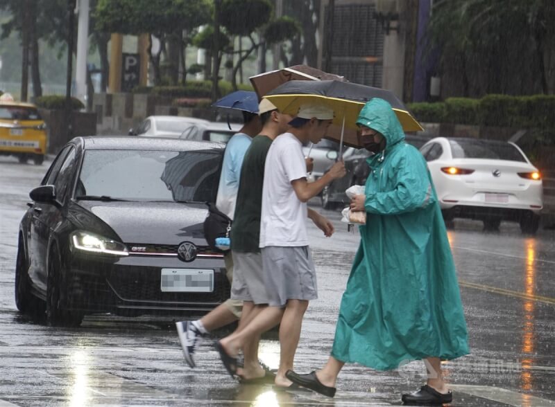 圖為高雄市苓雅區下起陣雨，民眾紛紛穿雨衣、撐傘遮擋雨勢。（中央社檔案照片）