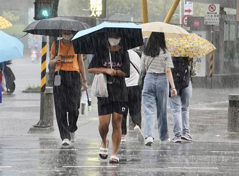 圖為高雄市新興區街頭民眾撐傘遮擋雨勢。（中央社檔案照片）