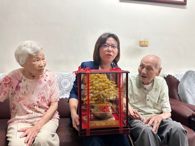 屏東市98歲鍾懃興（右）與96歲鍾邱喜鑾（左）今年喜迎結婚80年橡樹婚，是屏東結婚最久的一對，市長周佳琪（中）15日前往祝賀並致贈金樹，盼老夫妻健康安泰再創紀錄。（屏東市公所提供）中央社記者李卉婷傳真  112年9月15日