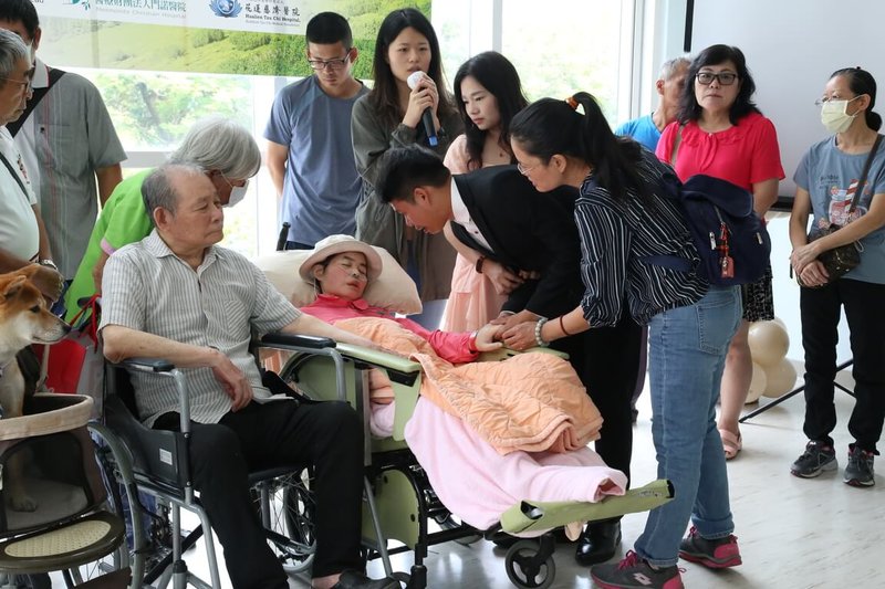 55歲蔡文娟(前左2)因肺腺癌末期住進門諾壽豐護理之家,愛好旅遊攝影的她一圓辦展夢,在護理之家展出37張攝影作品,17日開展當天,準備要結婚的姪兒和未婚妻也特地換上禮服看展,邀請蔡文娟提前當證婚人,並於耳邊傾訴道謝。(門諾醫院提供)中央社記者李先鳳傳真 112年9月18日