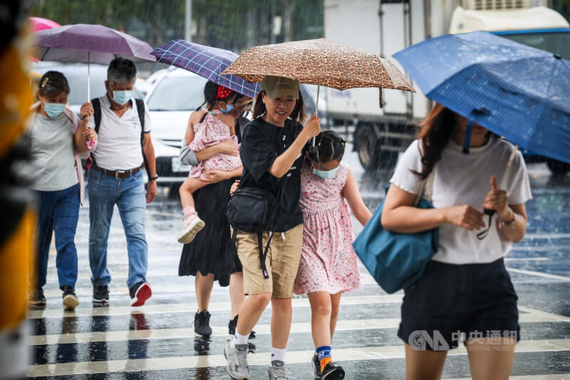 圖為台北市信義區民眾撐傘遮擋風雨。（中央社檔案照片）