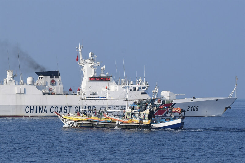 圖為一艘中國海警船20日在南海黃岩島附近透過跑馬燈警告、驅趕菲律賓漁船。（法新社）