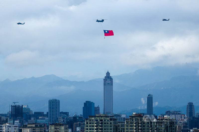 國慶將至，國軍28日展開空中全兵力預演，一架CH-47SD契努克運輸直升機（中）吊掛國旗飛越台北市上空。中央社記者王騰毅攝 112年9月28日