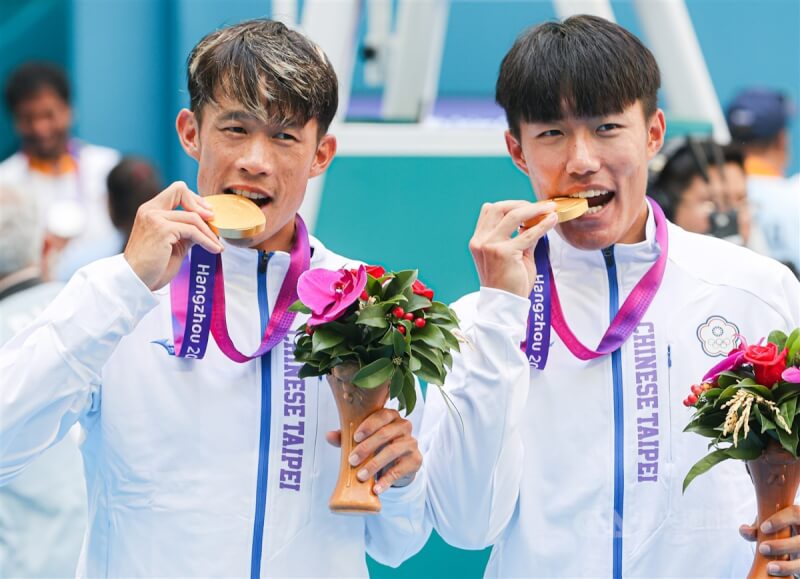 台灣網球選手許育修（右）、莊吉生（左）29日在杭州亞運網球男子雙打項目奪冠，兩人開心咬金牌慶祝勝利。中央社記者鄭清元攝 112年9月29日