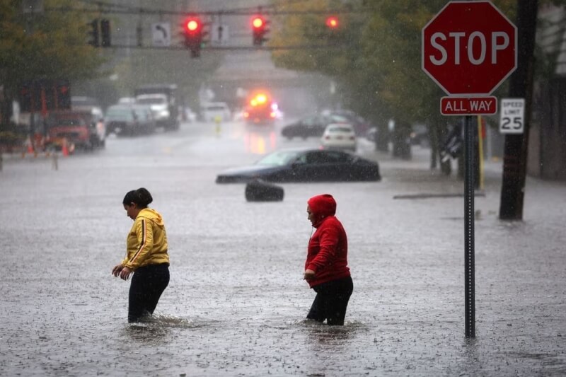 美國紐約市29日降下破紀錄的雨量。圖為水淹郊區道路，民眾在水中行走。（路透社）