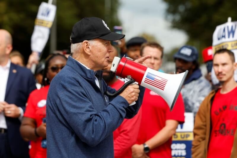 美國總統拜登（前）26日在密西根州大城底特律郊區的貝爾維爾加入聯合汽車工會罷工隊伍。（路透社）