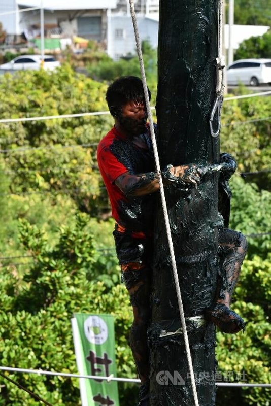 屏東恆春搶孤祈福友誼賽1日熱鬧登場，現場陽光普照天氣正好，吸引大批民眾圍觀賽況，參賽選手則賣力刮除棚柱上的牛油，以疊羅漢方式將攻旗手推向孤棚頂。中央社記者李卉婷攝  112年10月1日