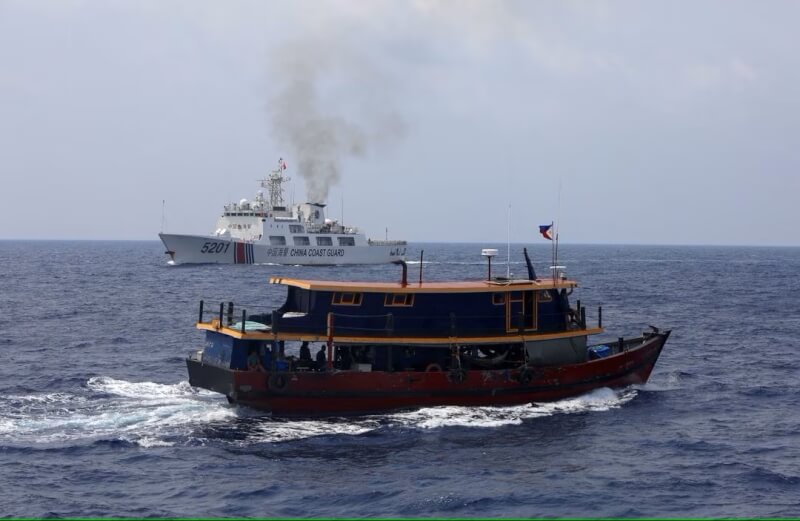 10月4日菲律賓的補給船隻（前）在南海仁愛暗沙執行運補任務時，一艘船身標示中國海警的船隻（後）也在附近航行。（路透社）