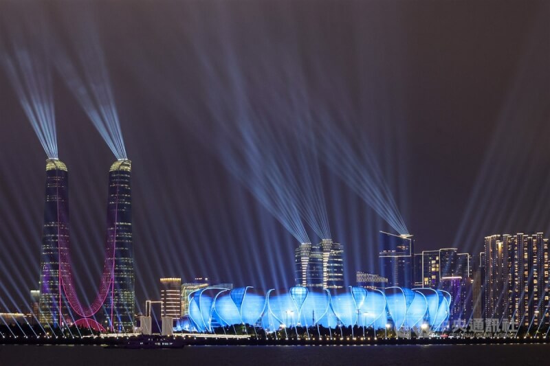杭州亞運在有「大蓮花」之稱的杭州奧體中心體育場（藍色燈光者）舉辦開幕式，場外也有燈光秀燦爛奪目。 （中央社檔案照片）